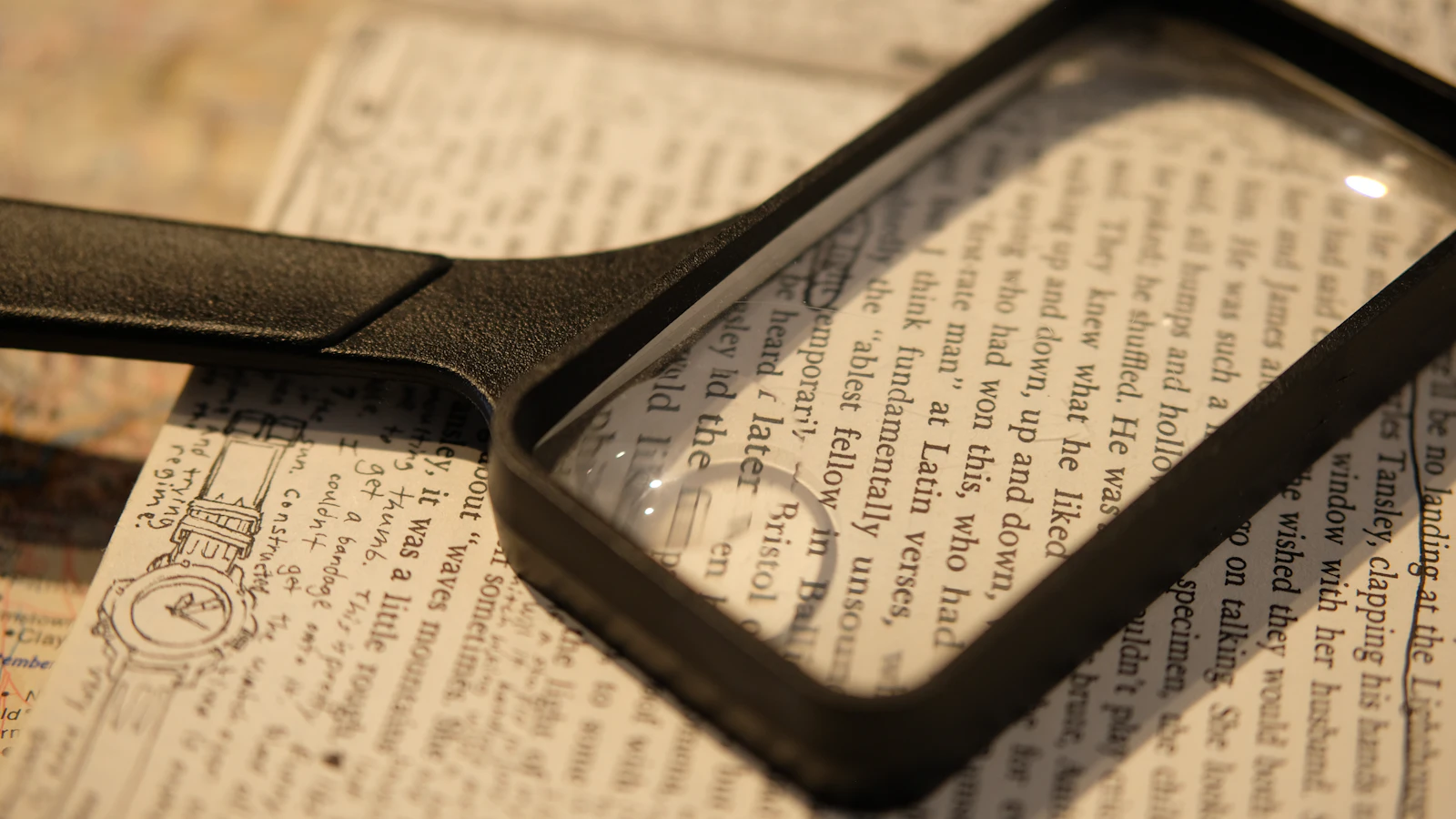 A rectangular magnifier lying across an open book of dense printed text, enlarging a few lines of it, with an engraving and handwritten notes on the facing page