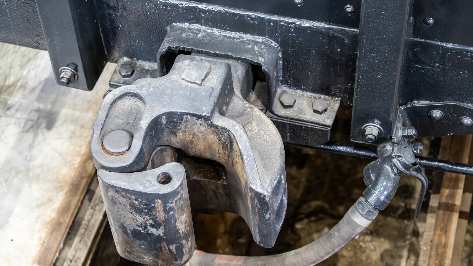 A rail knuckle coupler with its brake air hose and cock alongside, the standard joint that lets two separately built vehicles work as one and needs both connections made before anything moves
