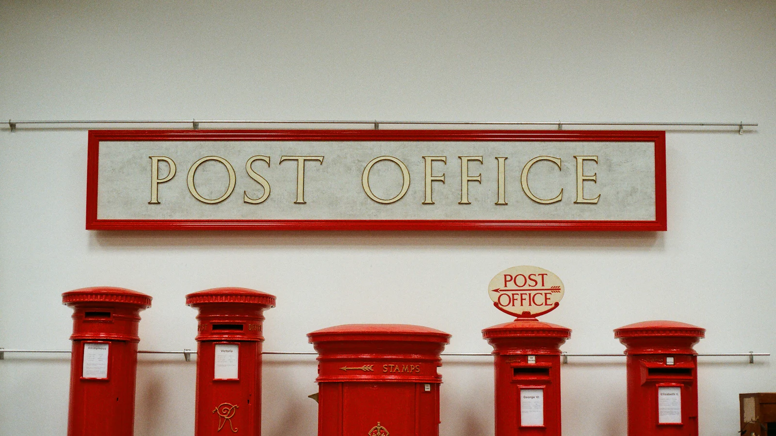 Five red pillar boxes lined up under a Post Office sign, each from a different reign and decade and every one a variation on a single design, which is the post's argument about trackers