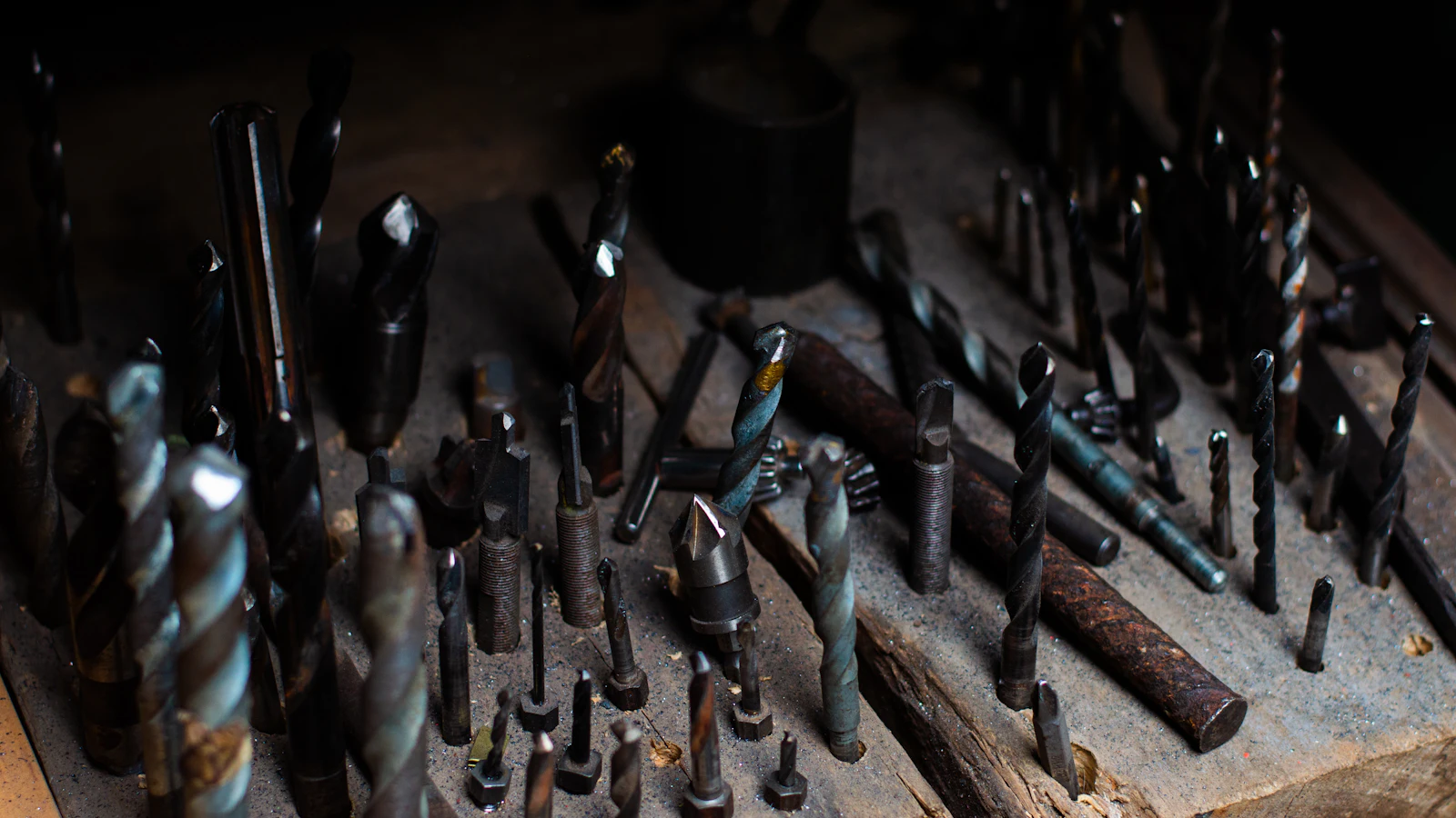 Dozens of drill bits and cutters of every size standing in a worn workshop block — the graded set you pick from when the only question that matters is which size actually fits the job